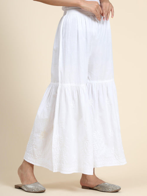 View a comfortable white Garara, with broad elastic waistband and flowing silhouette. Stylish ethnic bottom wear.