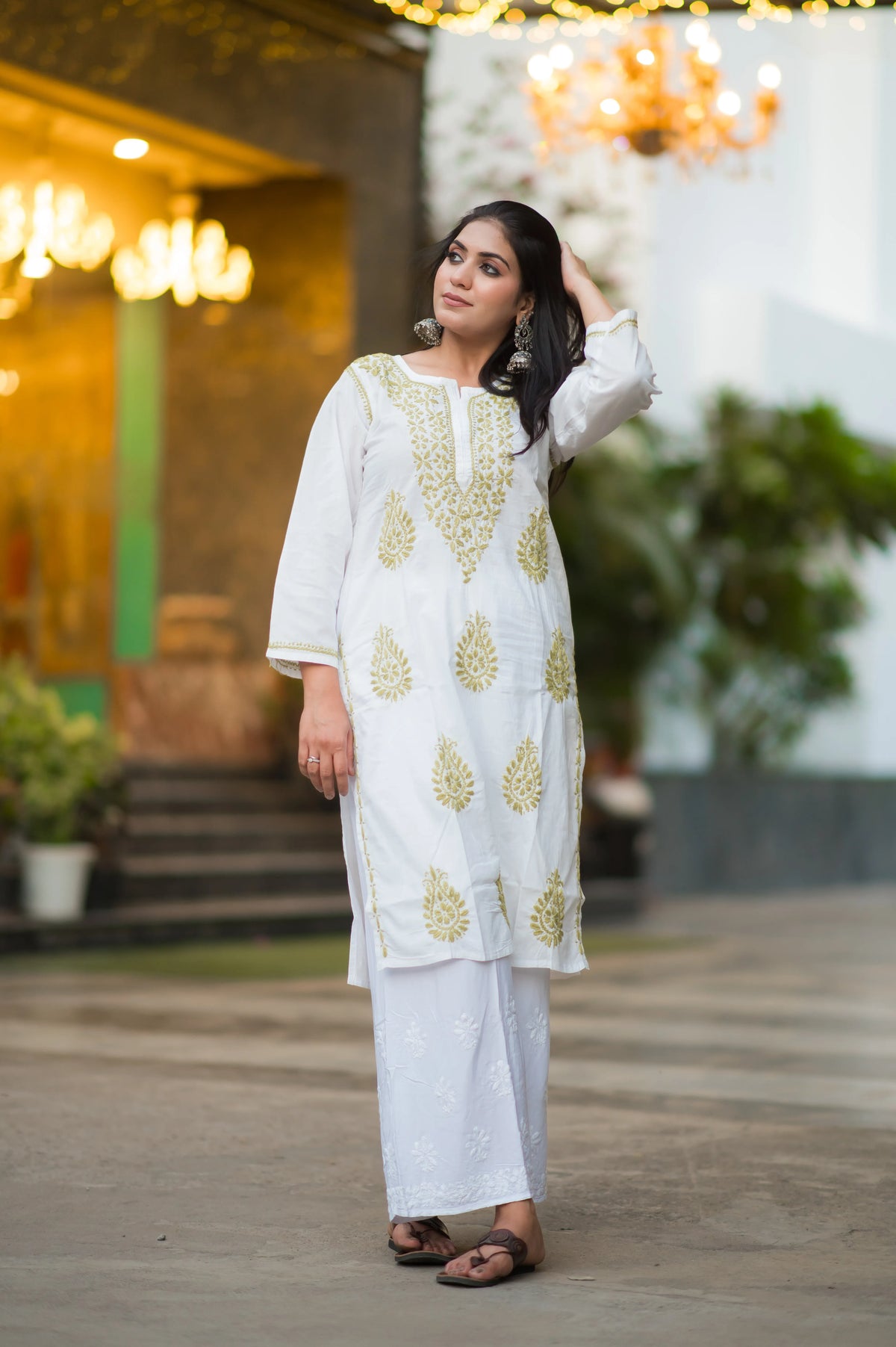 Side-front view of a woman wearing Snapfab's elegant white cotton Chikankari kurta with intricate beige embroidery.