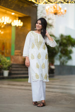 Front view of a smiling woman in Snapfab's breezy white Lucknowi Chikankari cotton kurta, adorned with exquisite beige hand embroidery, paired with matching palazzos.