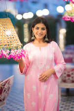 Front view of a woman smiling, elegantly dressed in a pink Lucknow Chikan kurta with white embroidery