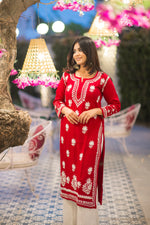 Angled view of a woman in a fashionable red kurta with a subtle white embroidered motif.