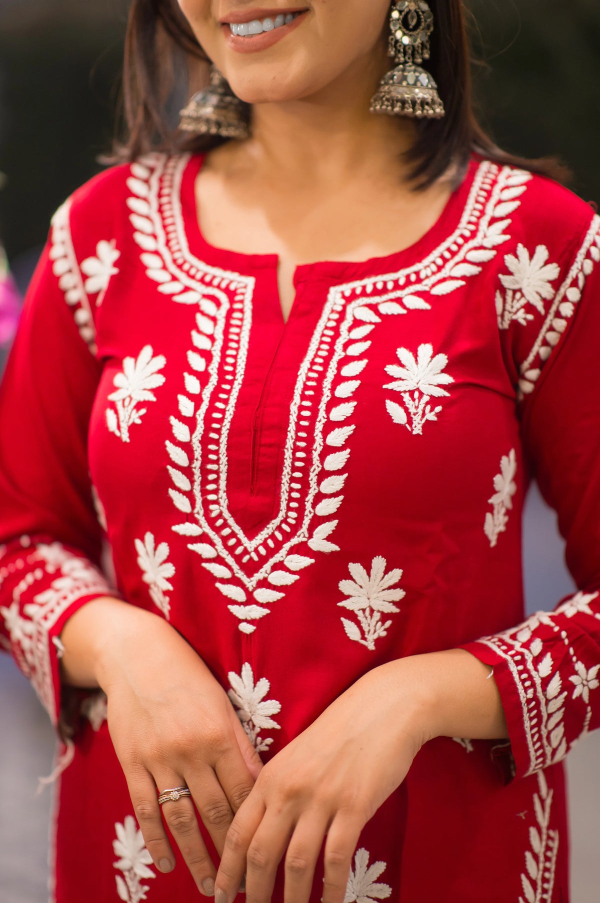 Close-up front view of a red kurta with textured white designer embroidery on the neckline.