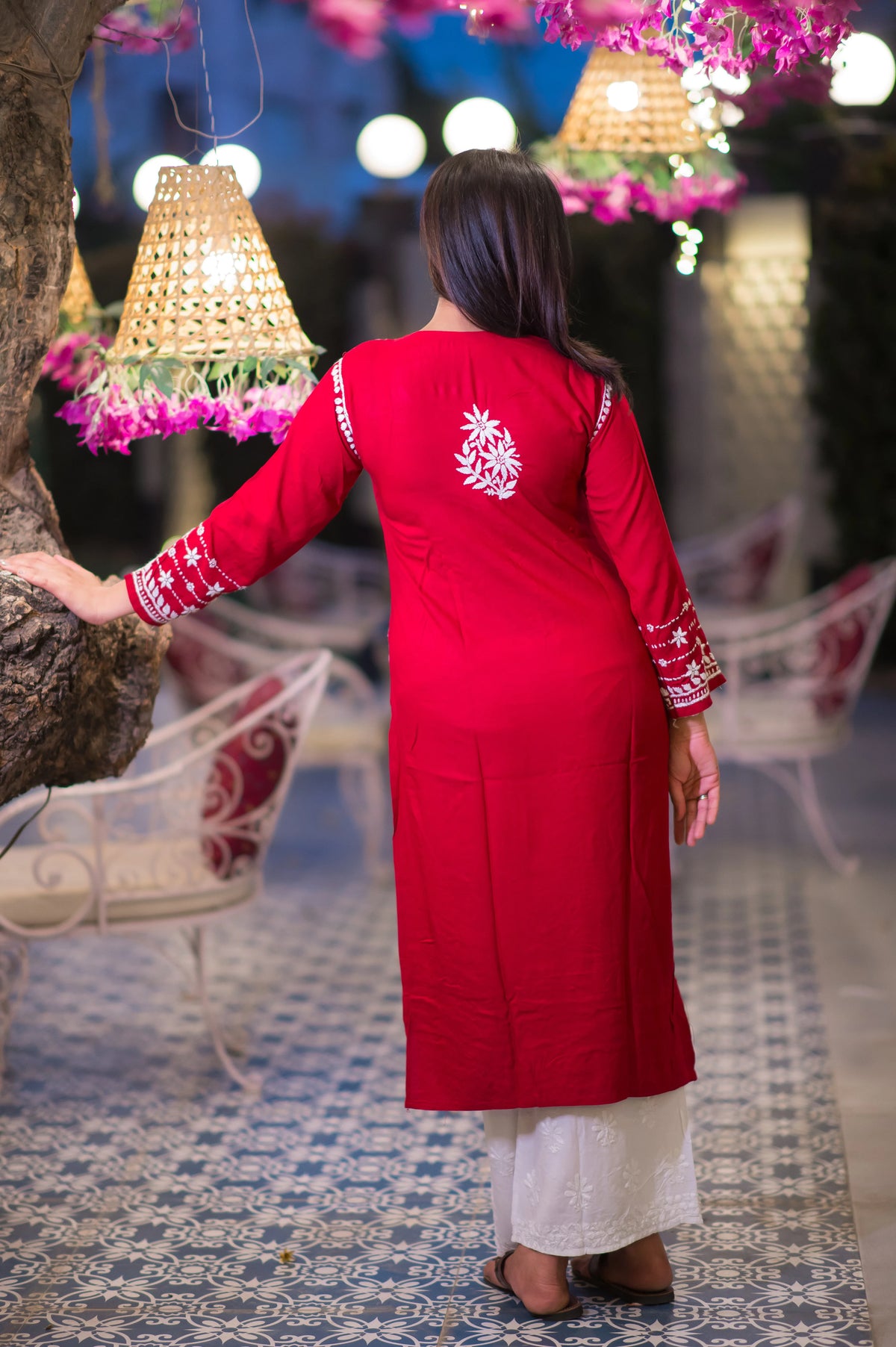 Back view of a woman in a traditional red kurta showcasing intricate white threadwork.
