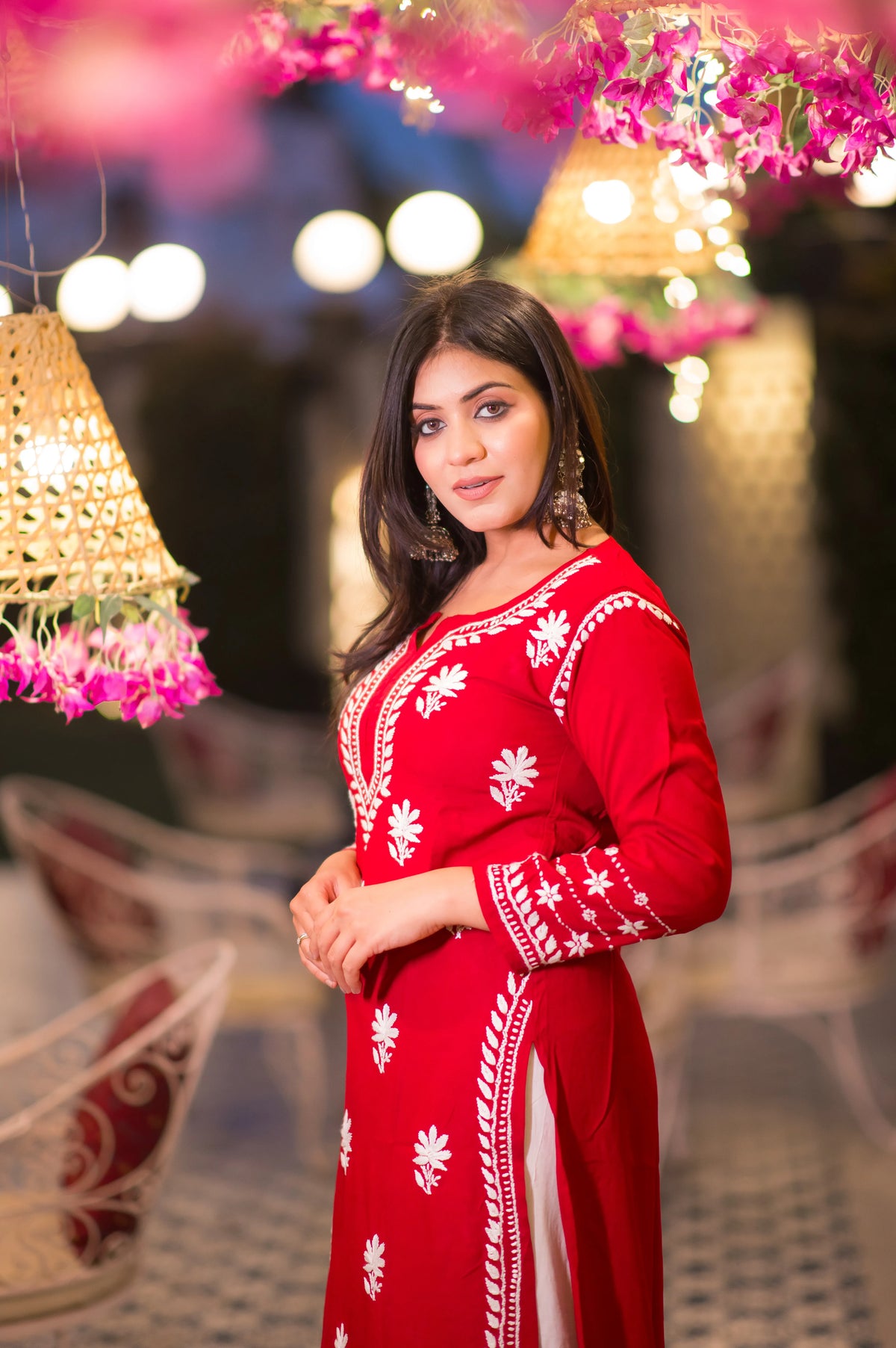 Side view of a woman in a elegant red kurta, showing the white embroidery and garment's fall.