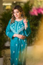 A side view captures a woman in a teal blue kurta with white vine-like embroidery along the front and sleeves.