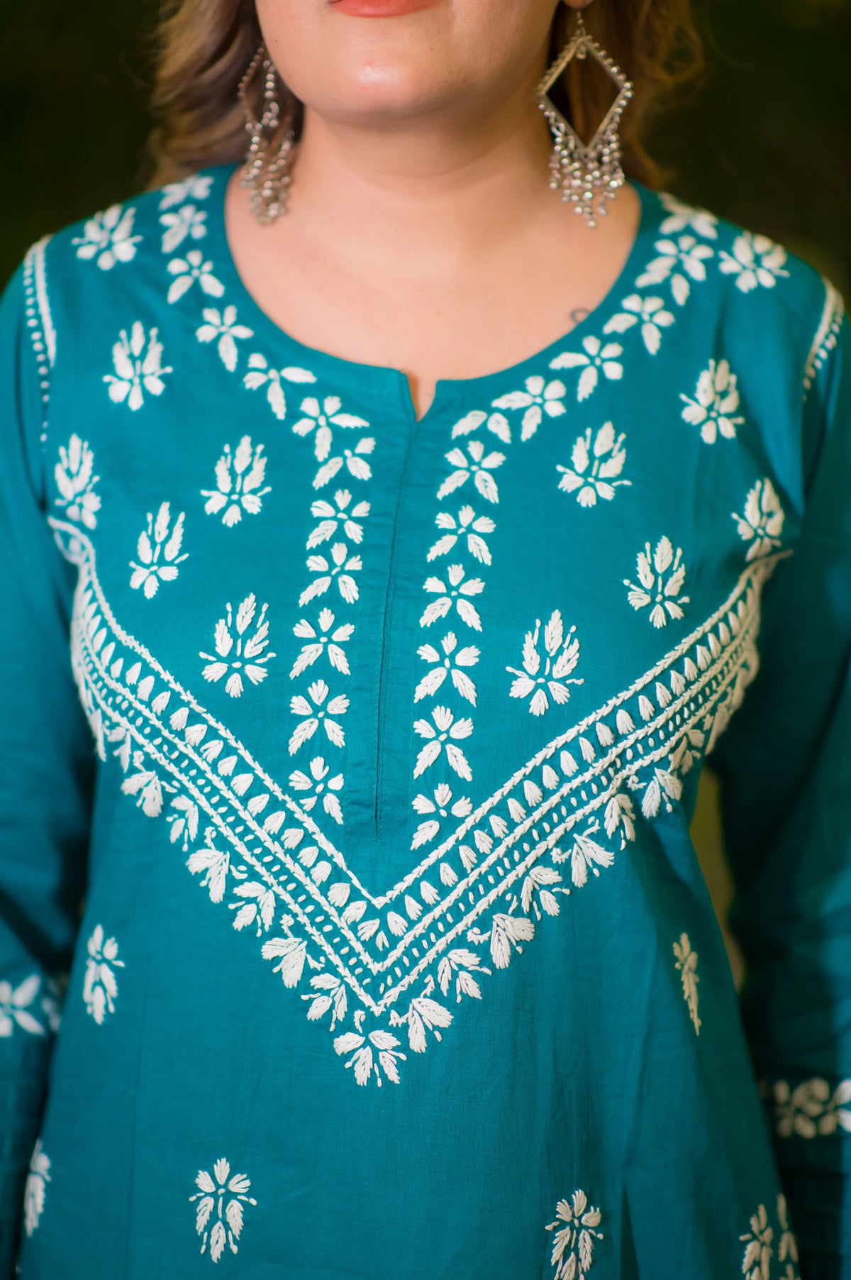 A close-up back view of a woman shows the white embroidery detail on the cuffs and back of the teal blue kurta.