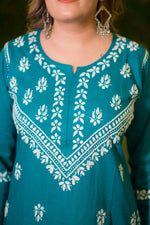 A close-up back view of a woman shows the white embroidery detail on the cuffs and back of the teal blue kurta.