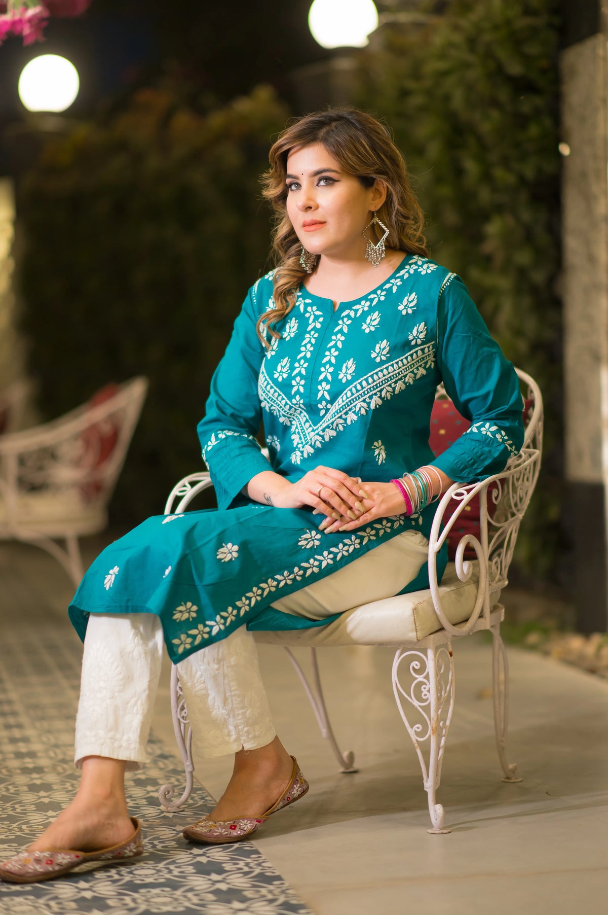 A seated view shows a woman in a teal blue kurta with white embroidery, paired with white patterned pants.