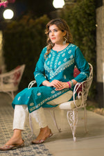 A seated view shows a woman in a teal blue kurta with white embroidery, paired with white patterned pants.