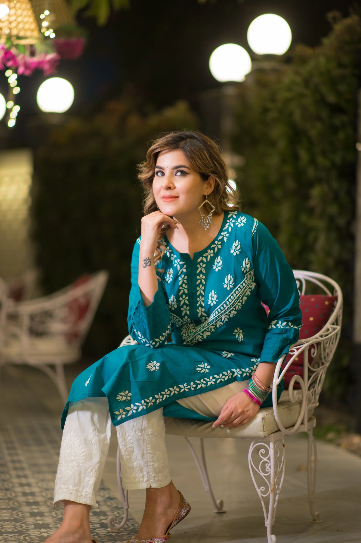 A seated close-up shows a woman in a teal blue kurta with white embroidery, resting her chin on her hand.