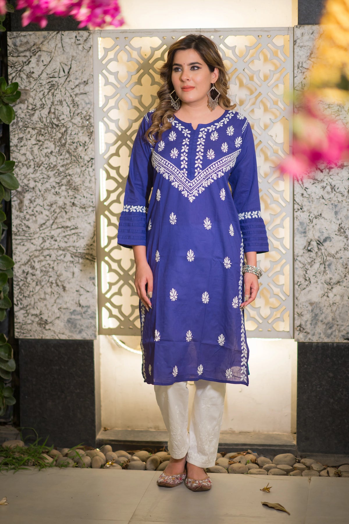 Front view of a woman in a blue riwayat kurta with white floral embroidery.