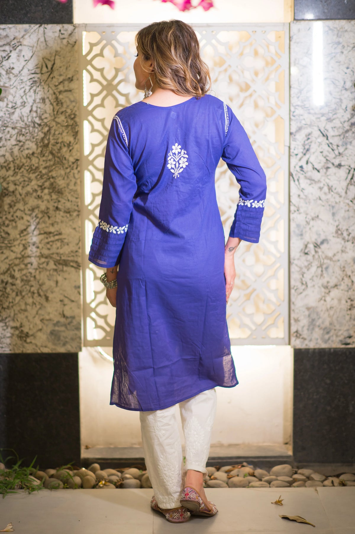 Back full shot of a woman in a blue riwayat kurta and white pants with white embroidery.