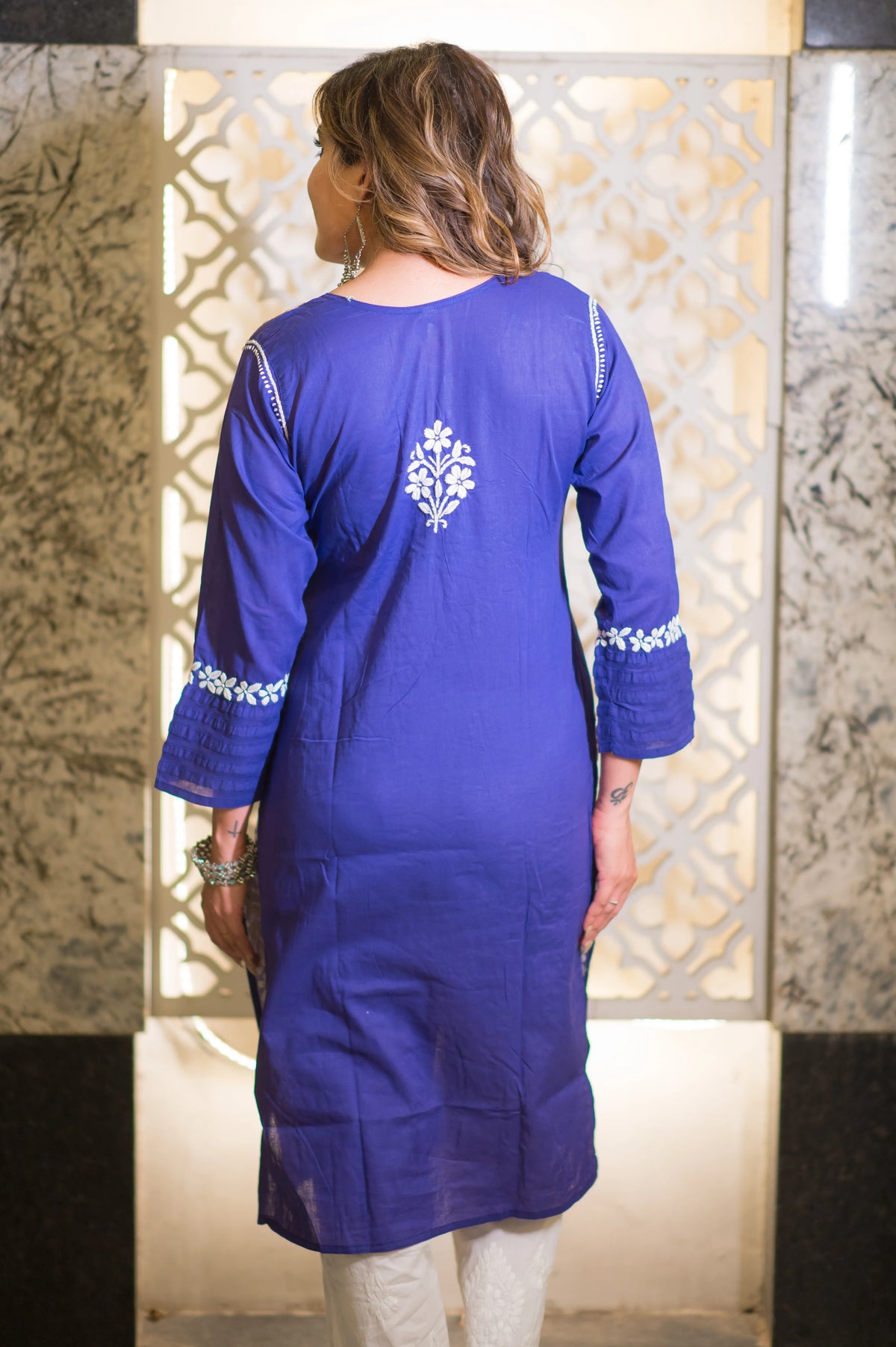 Close-up back view of the white floral design on a blue chikankari kurta.