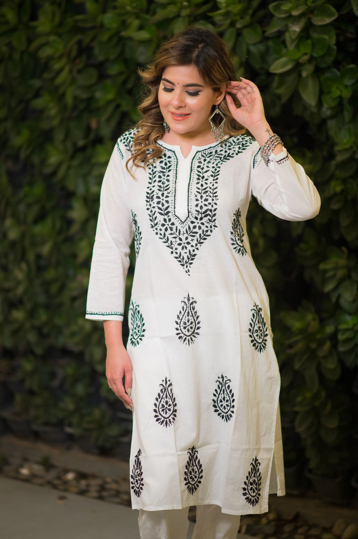 Full shot of a model in a white mulmul cotton kurta featuring black floral and paisley designs.