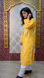 Side view of a vibrant yellow Chikankari kurti featuring intricate white hand embroidery, paired with classic white bottoms.