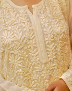 Close-up of exquisite Chikankari, pearl, and cut dana hand embroidery on a beige and yellow georgette kurti.