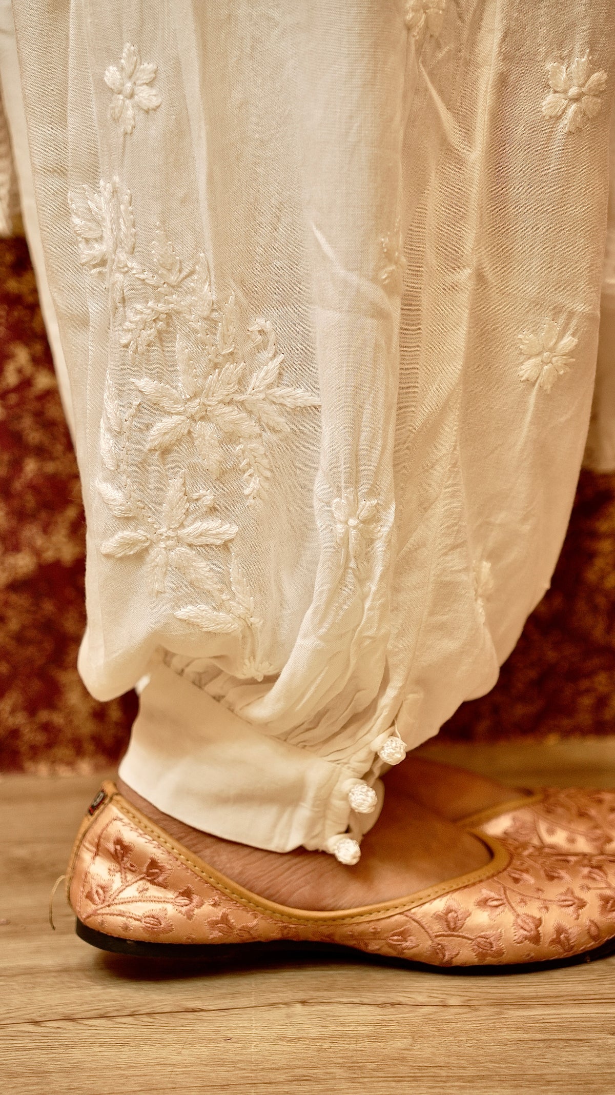 View the distinct silhouette of a white Afghani pant. Features authentic Chikankari handwork. Stylish bottom wear.