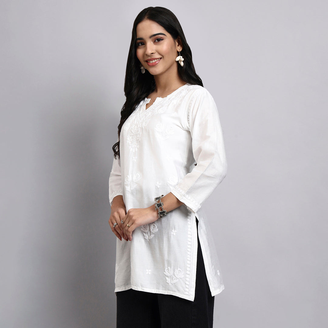 Woman wearing a white short kurta with black pants on a gray background