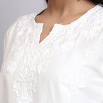 Close-up of a white textured chikankari kurta on a plain background