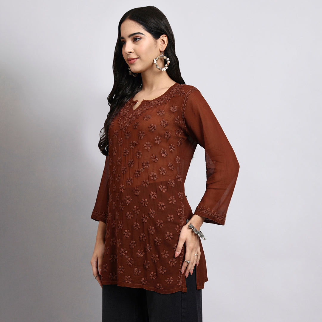 Woman wearing a brown floral patterned top against a gray background