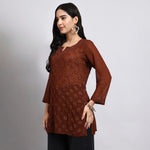 Woman wearing a brown floral patterned top against a gray background