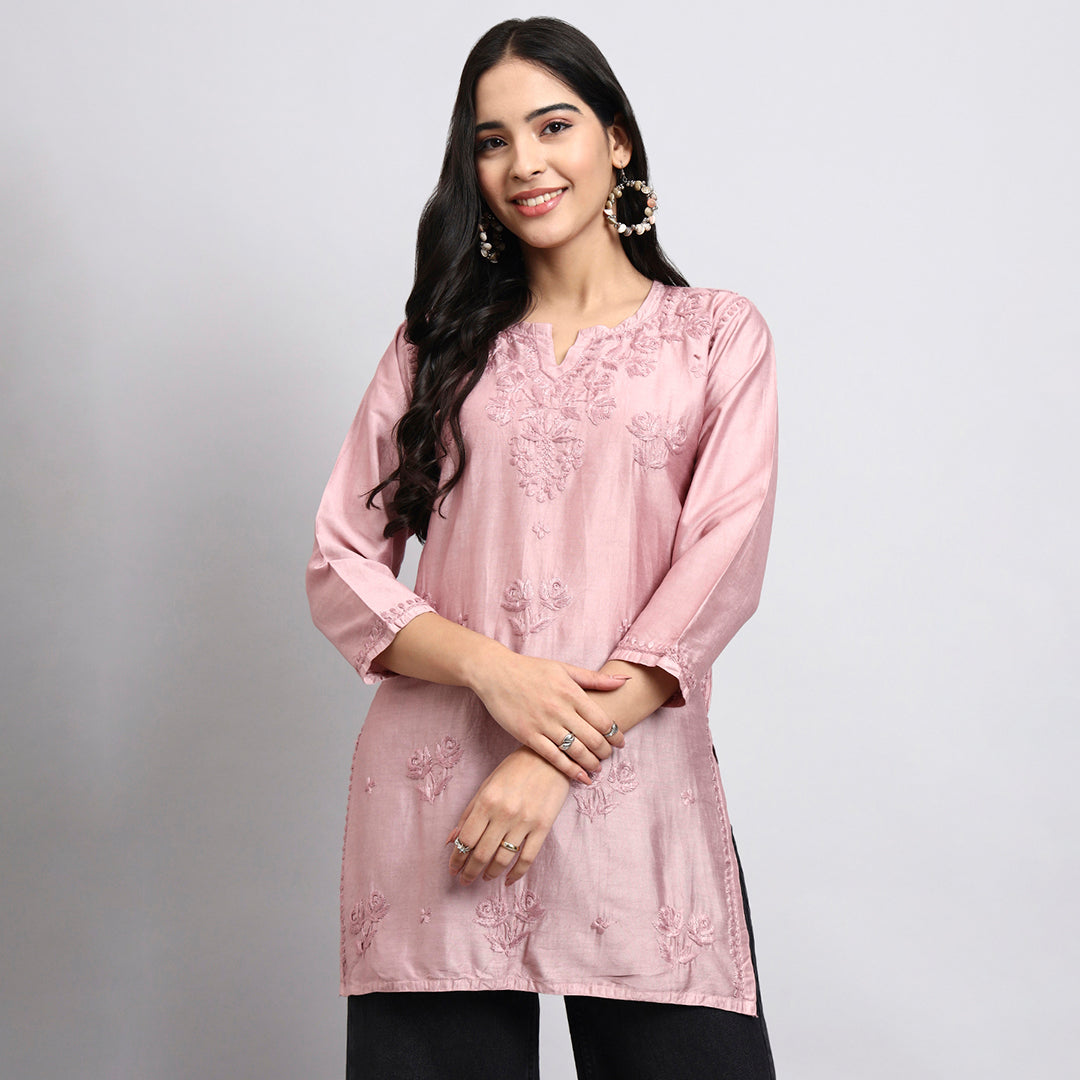 Woman wearing a pink embroidered kurta against a plain background