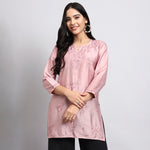 Woman wearing a pink embroidered kurta against a plain background