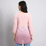 back View of Woman wearing a pink gradient top against a plain background