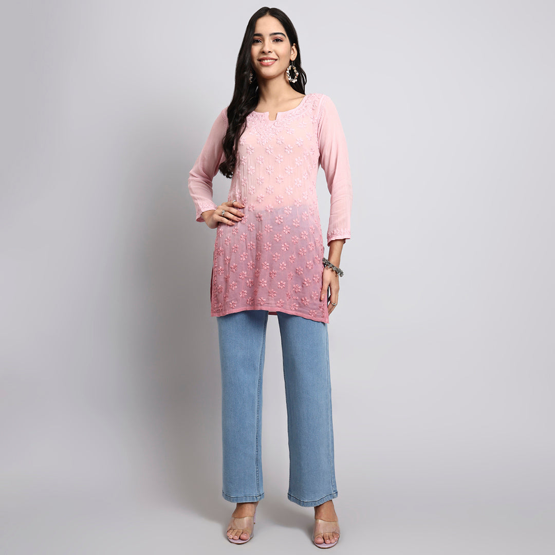 Woman wearing a pink top and blue jeans on a gray background