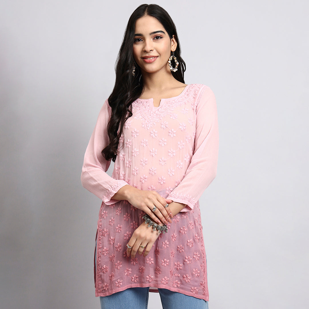 Woman wearing a pink embroidered kurta against a gray background