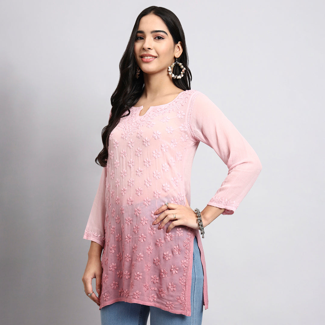 Woman wearing a pink floral top and blue pants on a gray background