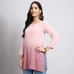 Woman wearing a pink floral top and blue pants on a gray background