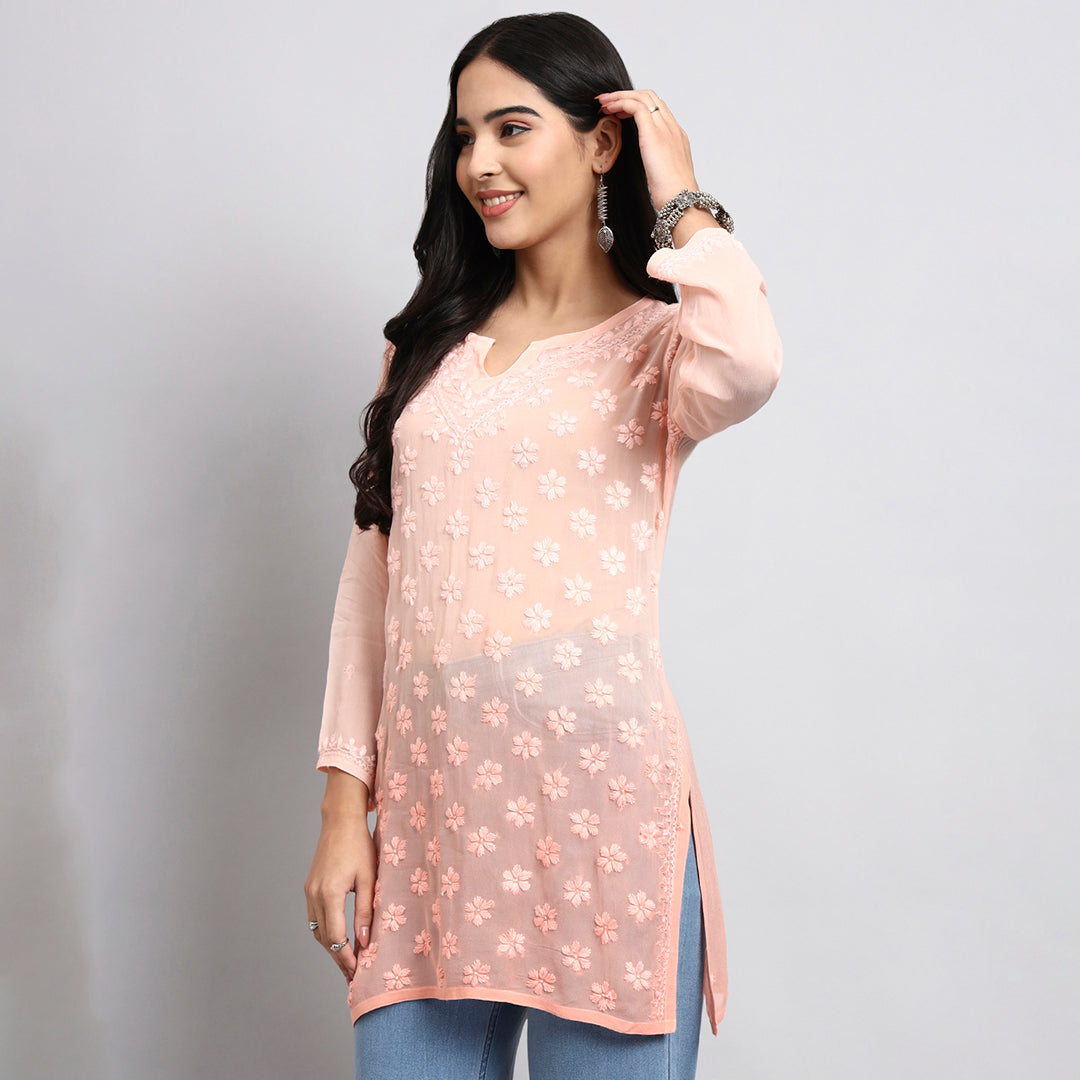 Woman wearing a light pink floral top against a gray background