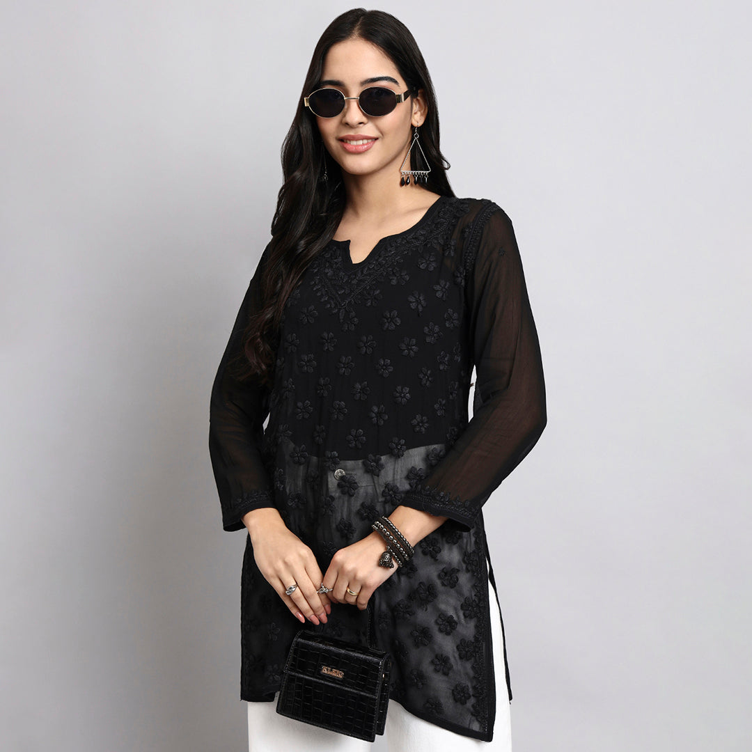 Woman wearing a black floral kurta with sheer sleeves against a gray background
