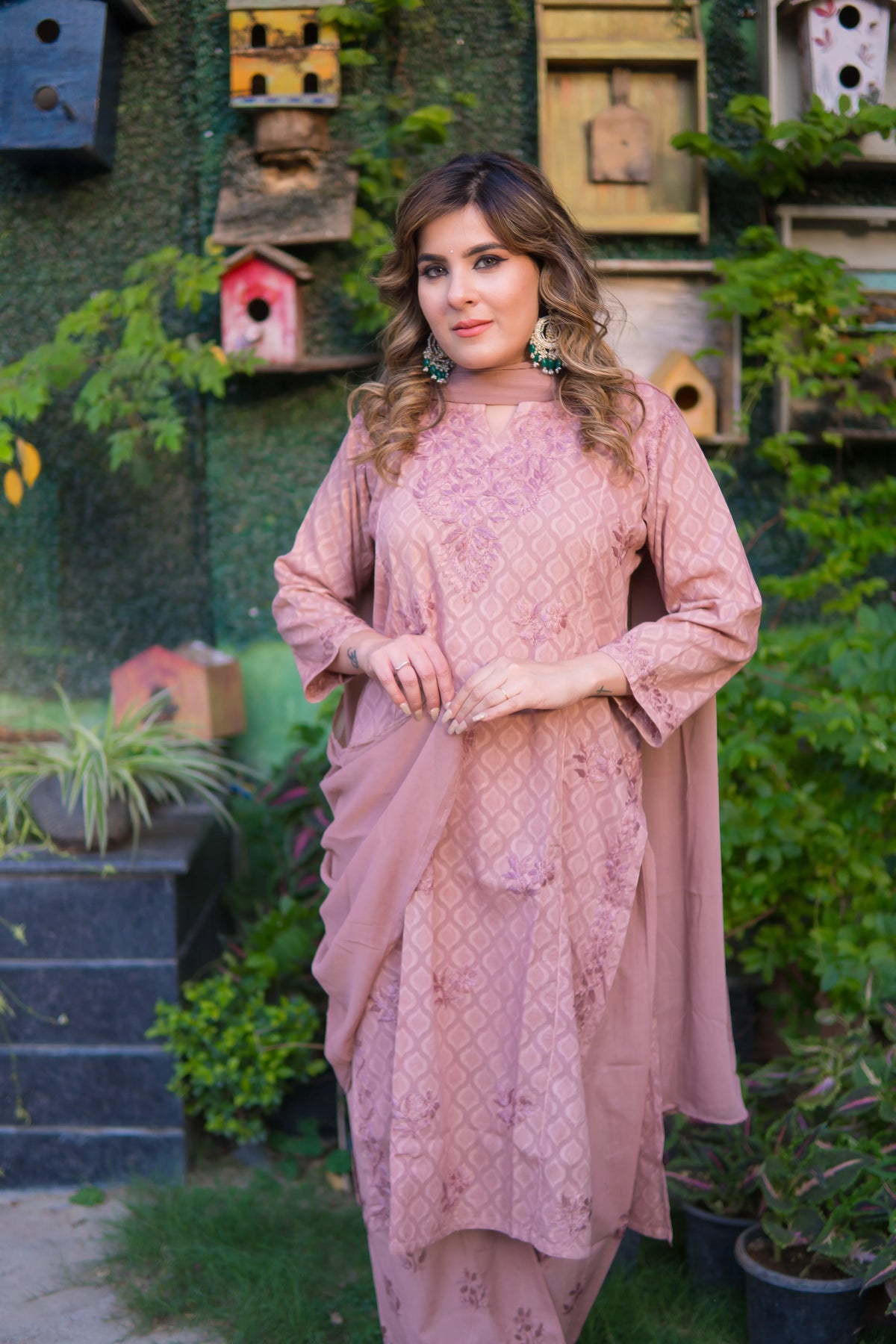A full shot shows a woman in a mauve pink kurta that has embroidery with matching pants.