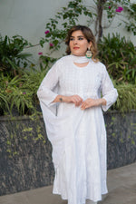 Angled view of a woman looking away, wearing a long, possibly chikankari white dress.