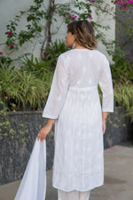 Back view of a woman holding a sheer white scarf, wearing a white anarkali dress that appears to have subtle texture.