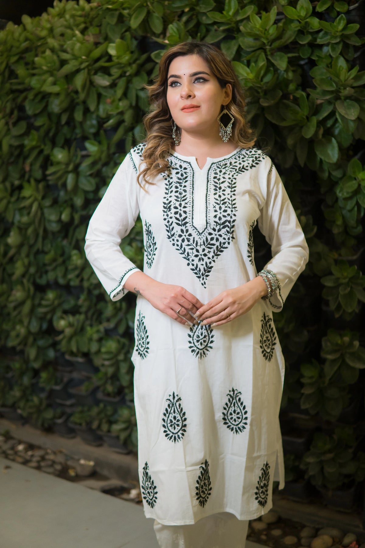 A model is shown in a front view, wearing a white kurti with a green traditional block print design, along with white pants.