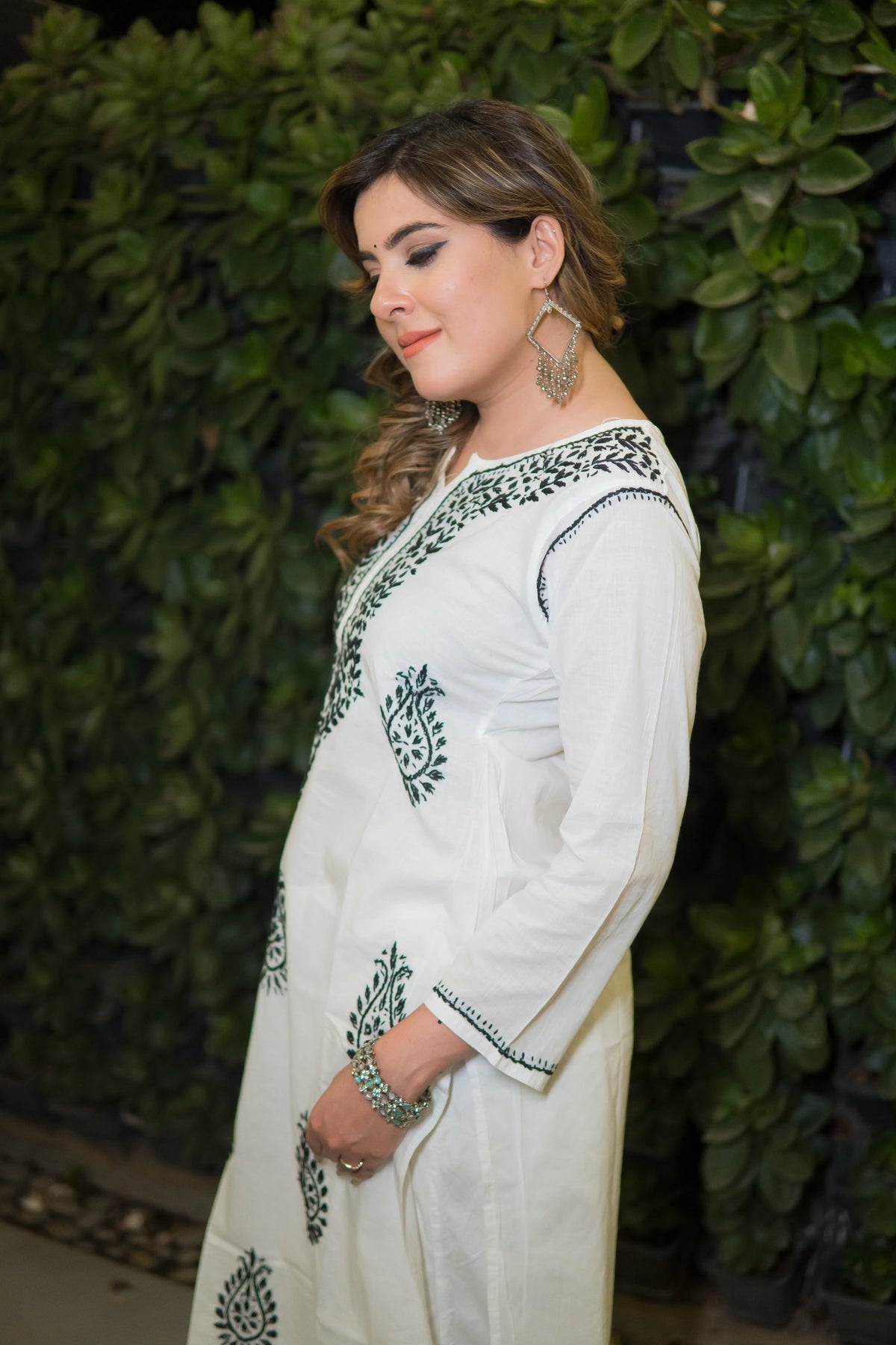 A side view captures a woman in a white mulmul kurti with green ornamental embroidery along the neckline and front.