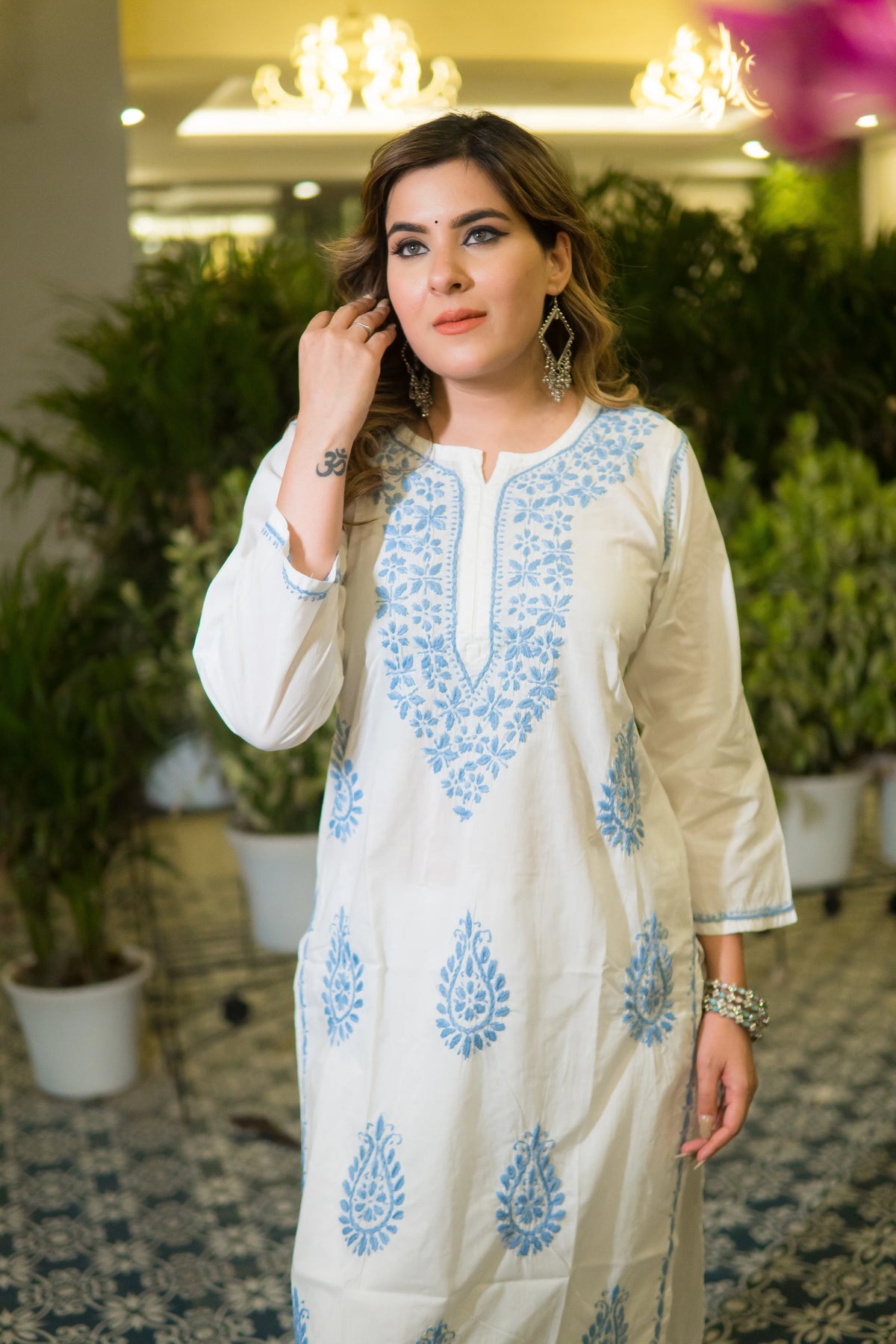 Side profile of a white chikankari kurta featuring fine blue embroidery on the sleeves and side panel.