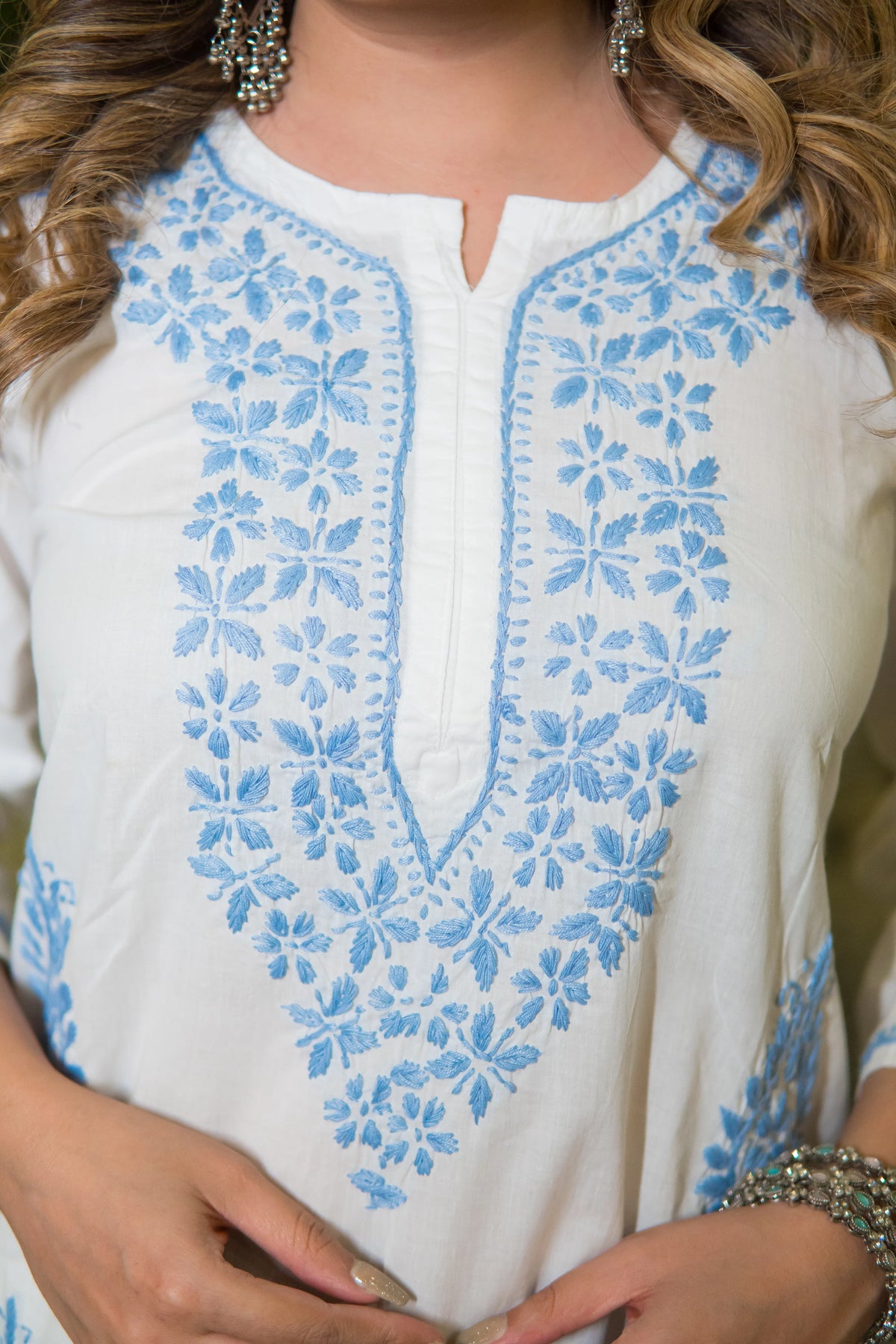 Partial side view of a white embroidered chikankari kurta highlighting fabric texture and design.