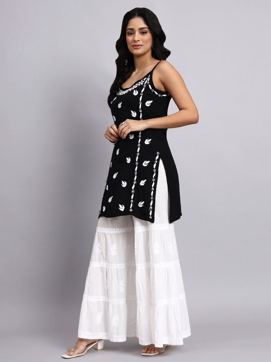 Side view of Woman wearing a black and white patterned top with a white skirt on a gray background