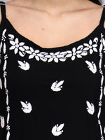 Close up view of Black top with white floral patterns on a plain background