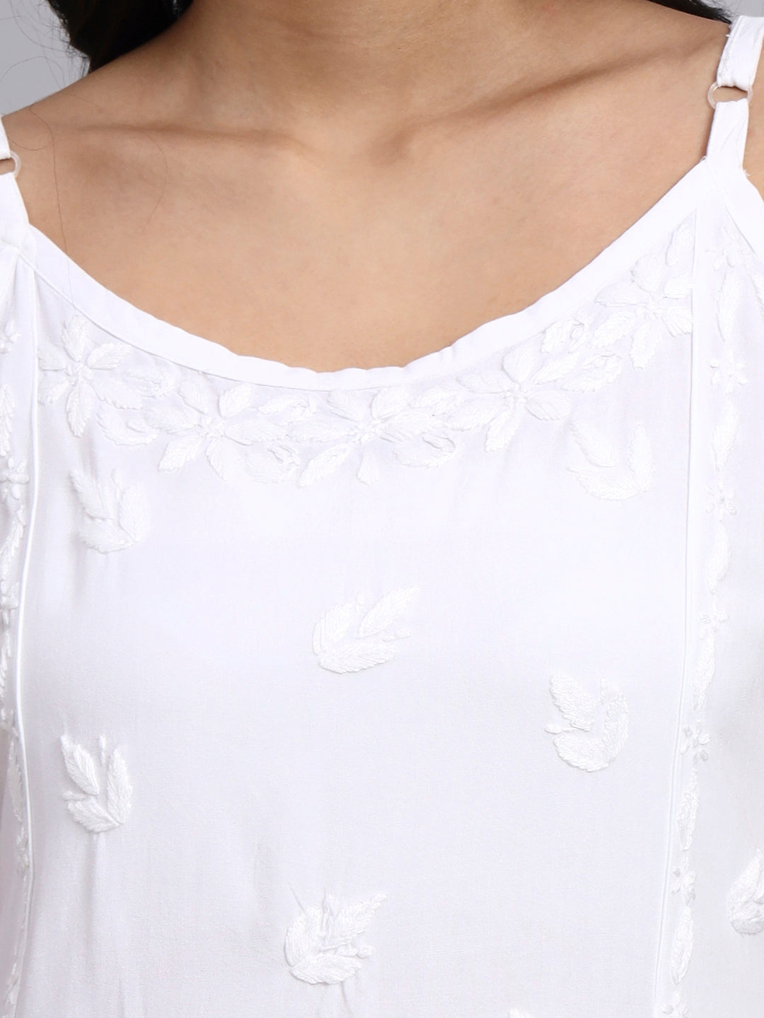 Close-up of a white top with delicate embroidery on a plain background