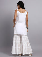 Back view of Woman wearing a white sleeveless kurti and layered white skirt on a gray background