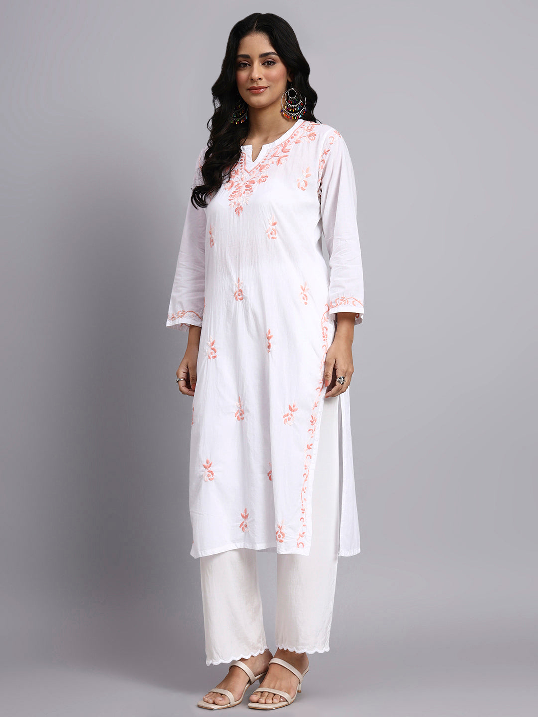 Side view of Woman wearing a white kurta with floral embroidery on a gray background