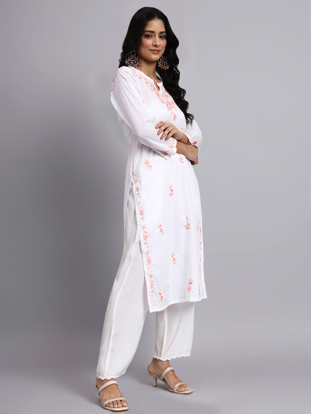 Woman wearing a white embroidered kurta with white pants on a gray background