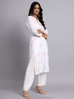 Woman wearing a white embroidered kurta with white pants on a gray background