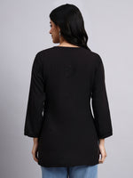Back view of Woman wearing a black long-sleeve top against a gray background