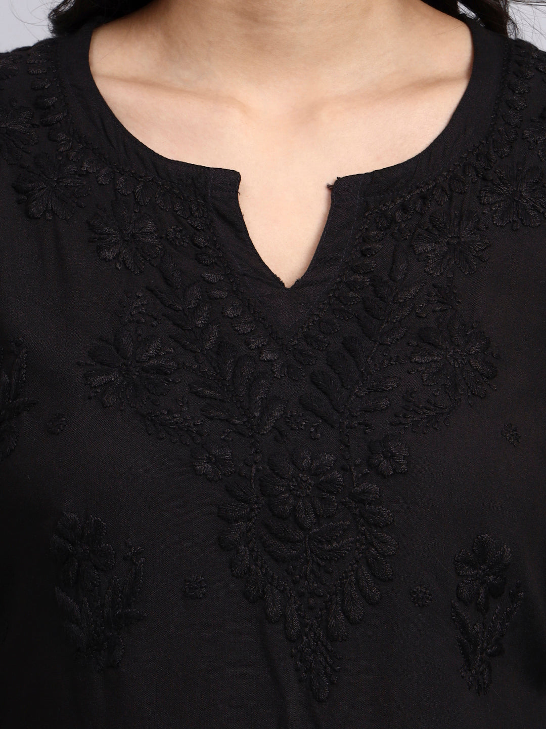 Close up view of Black top with intricate lace detailing on a plain background